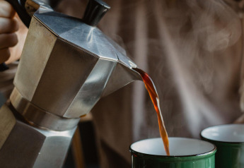 Een persoon schenkt hete koffie uit een mokapot in een groene mok en creëert zo een gezellige sfeer voor glamping ontspanning.