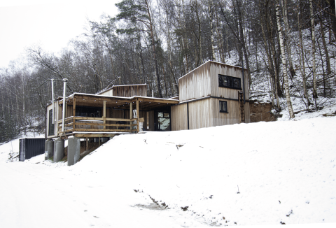 Pequeña casa de madera con jacuzzi en Cosy Cabins, bosque nevado de Limburg, Bélgica, junto a árboles.