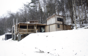 Kleine houten hut met jacuzzi bij Cosy Cabins in het besneeuwde Limburgse bos, België, tegen een helling.