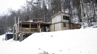 Piccola casa di legno con jacuzzi presso Cosy Cabins nella foresta innevata di Limburg, Belgio, vicino agli alberi.
