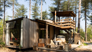 Cabaña moderna de madera Treetrunk con jacuzzi exterior y terraza en la azotea en medio del bosque.