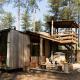 Moderne houten lodge Treetrunk met hot tub en dakterras, omgeven door hoge bomen in het bos.