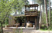 Foto del Treetrunk lodge con bañera de hidromasaje exterior, terraza y plataforma en las Ardenas de Limburgo.