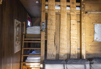Intérieur d'un hébergement glamping avec escalier en bois, lits superposés et murs en bois rustiques.