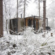 Cabane enneigée avec grandes baies vitrées et guirlande lumineuse en forêt de Limburg, Belgique.
