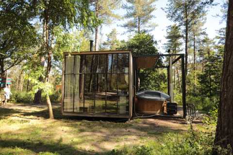 Cabaña clásica con bañera de hidromasaje en Cosy Cabins, bosque de Limburg, Bélgica, entre árboles.