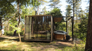 Cabaña clásica con bañera de hidromasaje en Cosy Cabins, bosque de Limburg, Bélgica, entre árboles.
