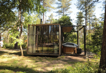 Cabina classica con vasca idromassaggio a Cosy Cabins nella foresta di Limburg, Belgio, tra gli alberi.