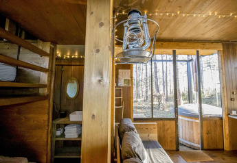 Sfeervolle houten hut in het bos met slaapzolder, zetel, oude lantaarn en hottub in Limburg, België.