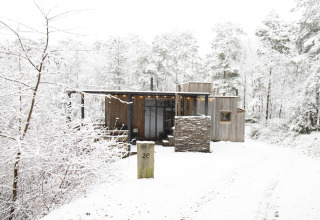 Moderne Holzhütte namens Water cabin + hot tub im verschneiten Wald von Limburg, Belgien.
