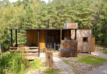 Water cabin e vasca idromassaggio di Cosy Cabins nella foresta di Limburg, Belgio, immersa nel verde.