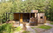 Water cabin met hottub bij Cosy Cabins in het bos van Limburg, België, houten huisje omringd door bomen.