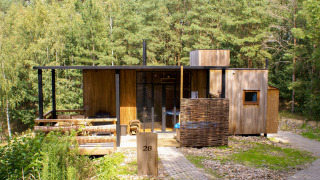 Water cabin with hot tub at Cosy Cabins, nestled in the forest of Limburg, Belgium, wooden exterior.