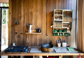 Cucina rustica in legno con lavandino in pietra e stoviglie in una baita Cosy Cabins nella foresta Limburg.