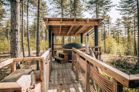 Treetop cabin with a hot tub and covered terrace in the forests of Limburg, Belgium, wooden walkway.