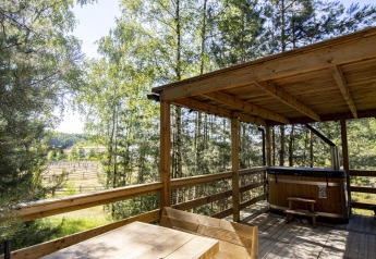 Udendørs træterrasse med overdækning, bord og varmtvandskar i skovene ved Cosy Cabins i Limburg, Belgien.
