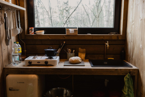 Cocina de cabaña rústica de madera con pan y fogón en Comfort Sweet + hot tub en el bosque de Limburg, Bélgica.