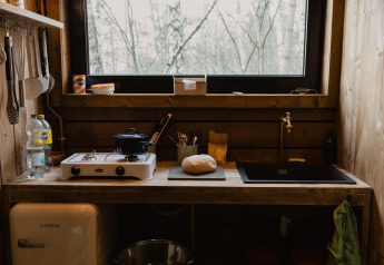 Cucina in legno di baita rustica con pane e fornello presso Comfort Sweet + hot tub nella foresta di Limburgo, Belgio.