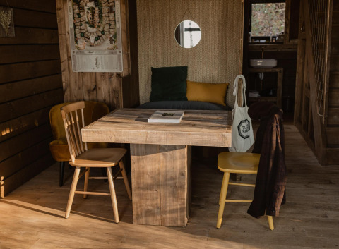 Comfort Sweet hut met houten tafel en stoelen in Cosy Cabins, Limburgse bossen, België.