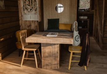 Cabina Comfort Sweet con tavolo e sedie in legno rustico alle Cosy Cabins nella foresta di Limburg, Belgio.
