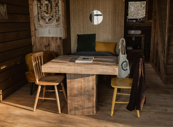 Cabaña Comfort Sweet con mesa y sillas de madera rústica en Cosy Cabins, bosque de Limburg, Bélgica.