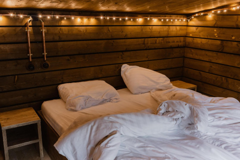 Acogedora habitación de cabaña con cama doble y luces cálidas en Comfort Sweet, Limburg, Bélgica.