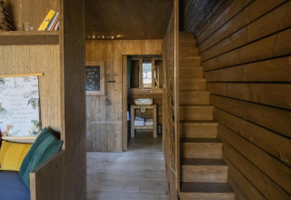 Interior de madera de la cabaña Comfort Sweet con escalera, sofá y lavabo en Cosy Cabins, Limburg.