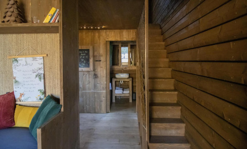 Træinteriør i Comfort Sweet-hytten med trapper, sofa og håndvask i Cosy Cabins i Limburg-skoven.