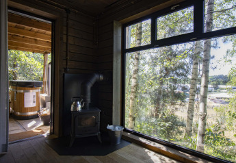 Uitzicht vanuit de Comfort Sweet cabin met houtkachel, groot raam en hottub in het Limburgse bos.