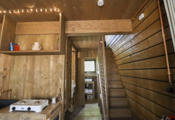 Vista interna della cabina Comfort Classic con pareti di legno e scala da Cosy Cabins nella foresta di Limburgo.
