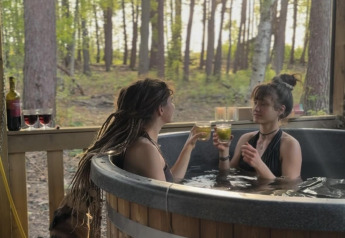 Twee vrouwen genieten van een drankje in het bubbelbad bij Comfort Classic, Cosy Cabins, Limburg, België.