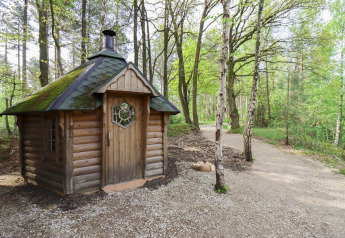 Comfort Classic + sauna cottage bij Cosy Cabins in het Limburgse bos, België, omringd door groene bomen.