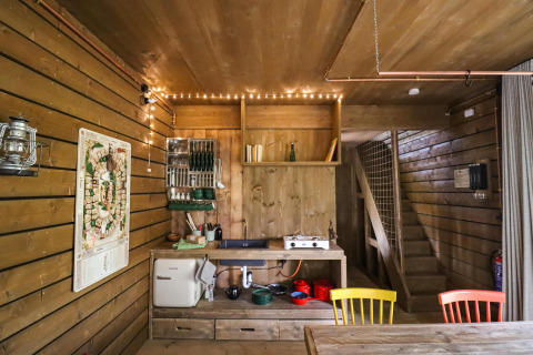 Acogedora cabaña Comfort Classic + sauna con cocina de madera y sillas de colores en el bosque de Limburg, Bélgica.