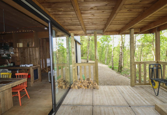 Baita in legno con veranda coperta, vista su sentiero nel bosco e zona pranzo, Cosy Cabins, Limburgo.