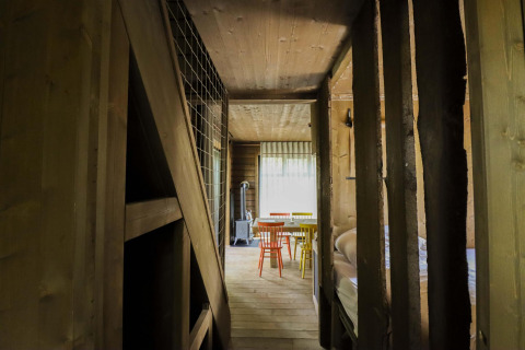 Interior de madera de la cabaña Comfort Classic + sauna en Cosy Cabins, bosque de Limburgo, Bélgica, con sillas de colores.