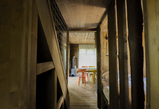 Houten interieur van Comfort Classic + sauna cottage bij Cosy Cabins in het Limburgse bos, België, met gekleurde stoelen.