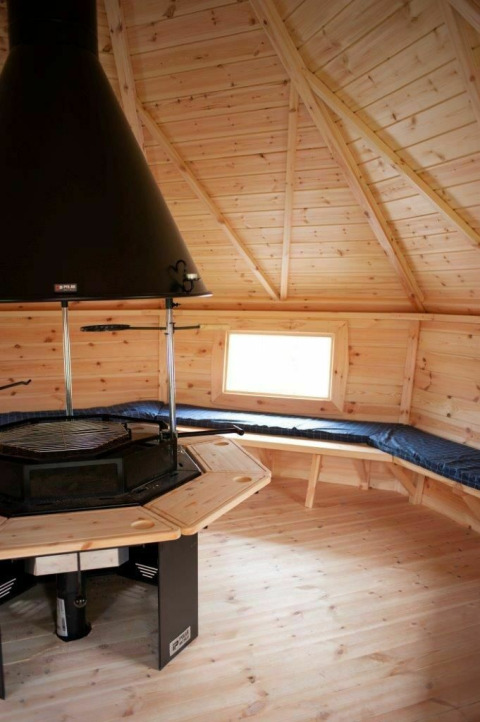 Interior view of Veluwe Villa lodge with wooden ceiling and grill at Holiday park De Boshoek, Netherlands.