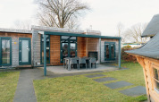 Vista exterior de Veluwe Villa con terraza cubierta y muebles de jardín en Holiday park De Boshoek, Países Bajos.