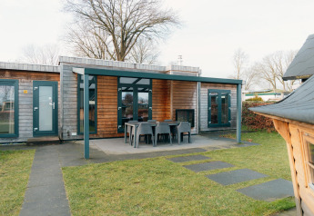 Outdoor view of Veluwe Villa with covered terrace and garden furniture at Holiday park De Boshoek, Netherlands.