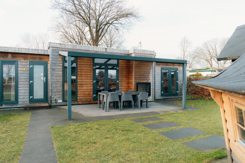 Buitenaanzicht van Veluwe Villa met overdekt terras en tuinmeubilair bij Holiday park De Boshoek, Nederland.