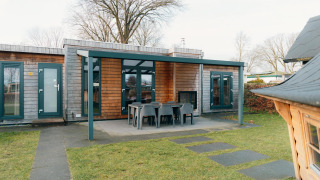 Außenansicht der Veluwe Villa mit überdachter Terrasse und Gartenmöbeln im Ferienpark De Boshoek, Niederlande.