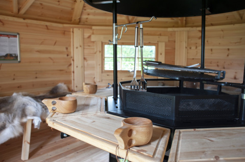 Interieur van houten lodge met centrale grill en houten bekers bij Veluwe Villa + sauna, De Boshoek, Nederland.