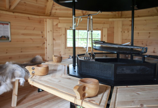 Interior of wooden lodge with central grill, wooden cups, and fur throws at Veluwe Villa + sauna, De Boshoek.