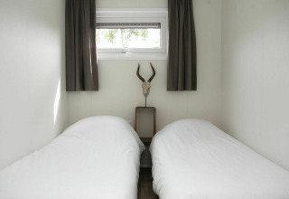 Two single beds with white bedding in a small room at Veluwe Villa + sauna, Holiday park De Boshoek, Netherlands.