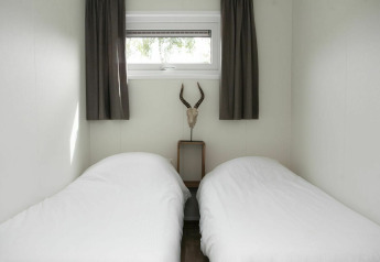 Zwei Einzelbetten mit weißen Bettdecken im Veluwe Villa + Sauna, Holiday park De Boshoek, Niederlande.