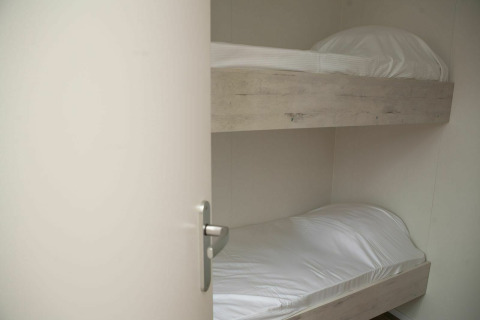 Et værelse med to køjesenge med hvide lagner på Veluwe Villa + sauna i Holiday park De Boshoek, Holland.