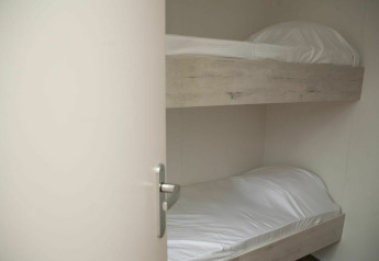 Chambre avec deux lits superposés munis de draps blancs à Veluwe Villa + sauna, Holiday park De Boshoek, Pays-Bas.
