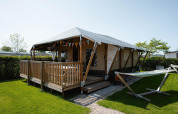 Cabaña Villatent Cottage con terraza de madera y hamaca en Camping de Molenhoek, Países Bajos, vista exterior.