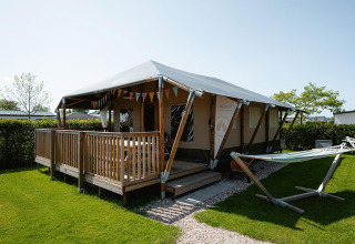 Cabaña Villatent Cottage con terraza de madera y hamaca en Camping de Molenhoek, Países Bajos, vista exterior.
