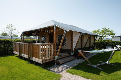Villatent Cottage lodge with wooden deck and hammock at Camping de Molenhoek, Netherlands, outdoor view.